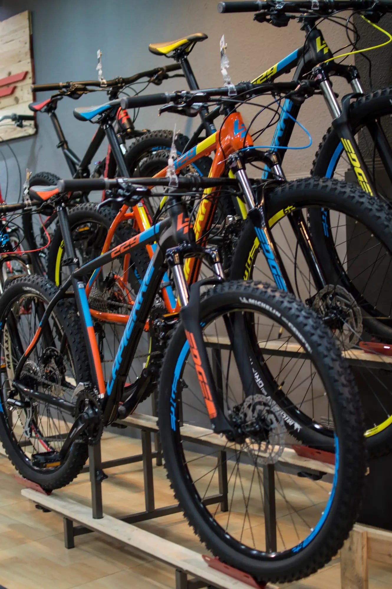 Bicicleta de montaña naranja y azul con marco negro, neumáticos con tacos y frenos de disco