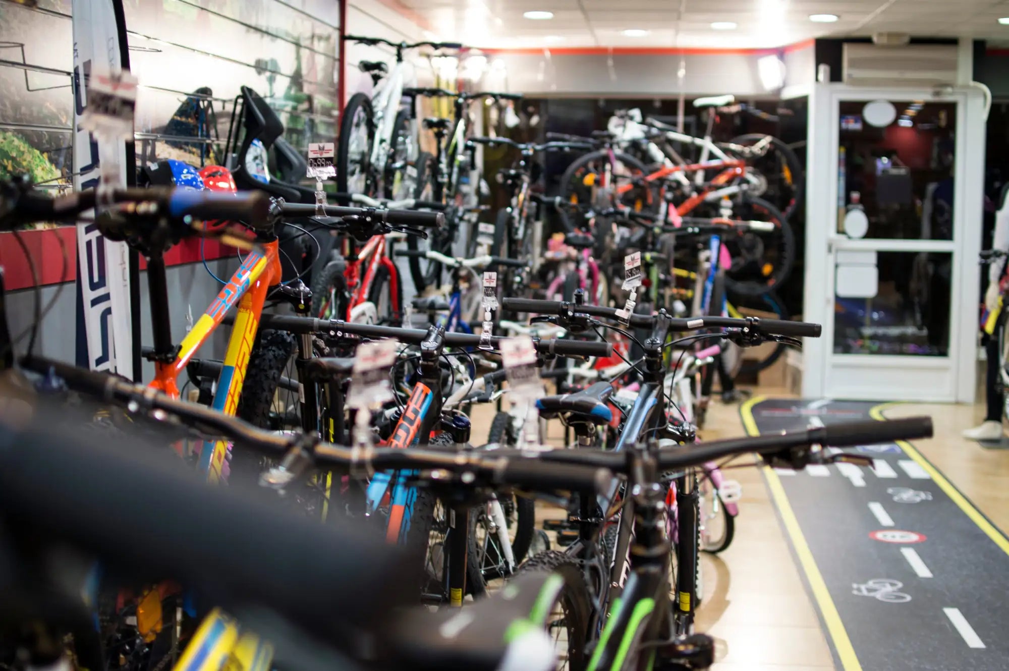 Filas de bicicletas de montaña coloridas con manillares negros y cuadros vibrantes recorren el pasillo de la tienda.