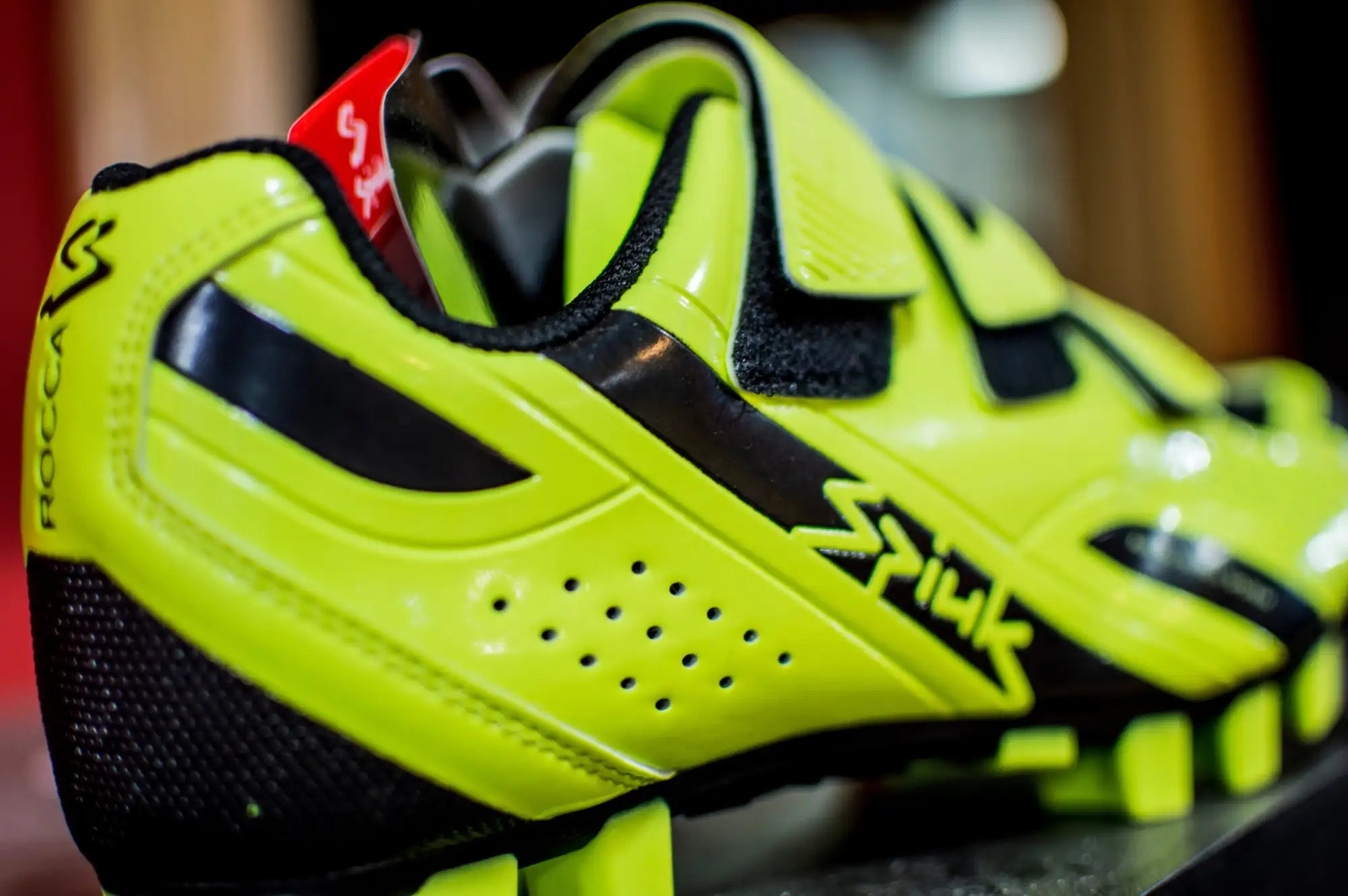 Zapatilla de ciclismo vibrante en neón amarillo y negro con un diseño aerodinámico elegante que incluye paneles de ventilación perforados.